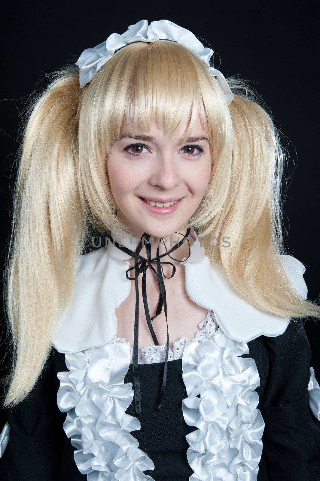 Portrait of young girl in anime lolita suit on black background