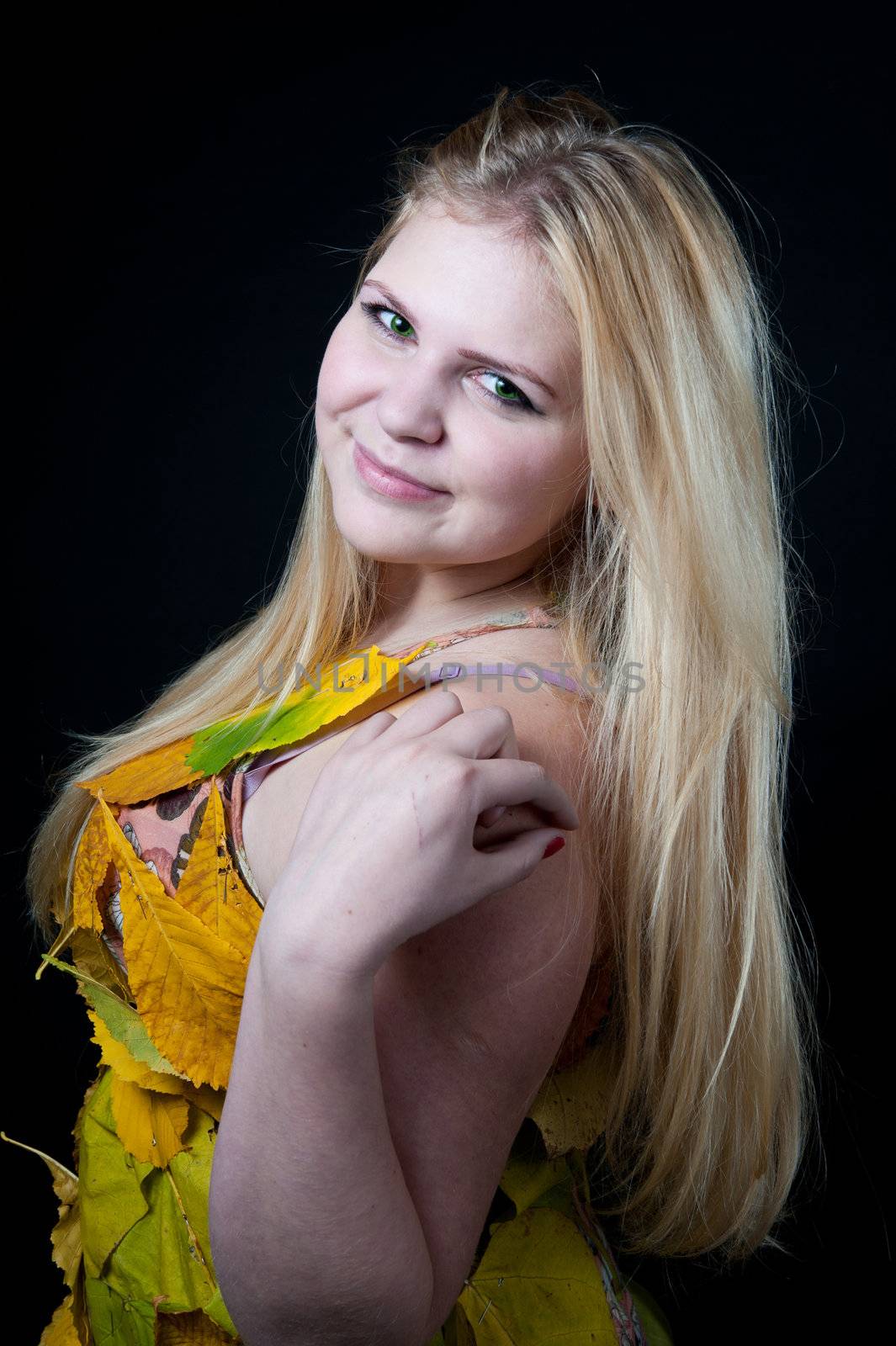 portrait girl in dress decorated with autumn leaves on black background