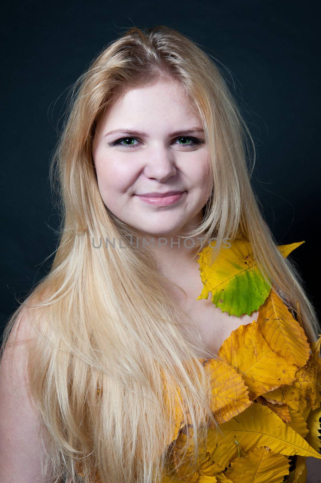 portrait girl in dress decorated with autumn leaves on black background