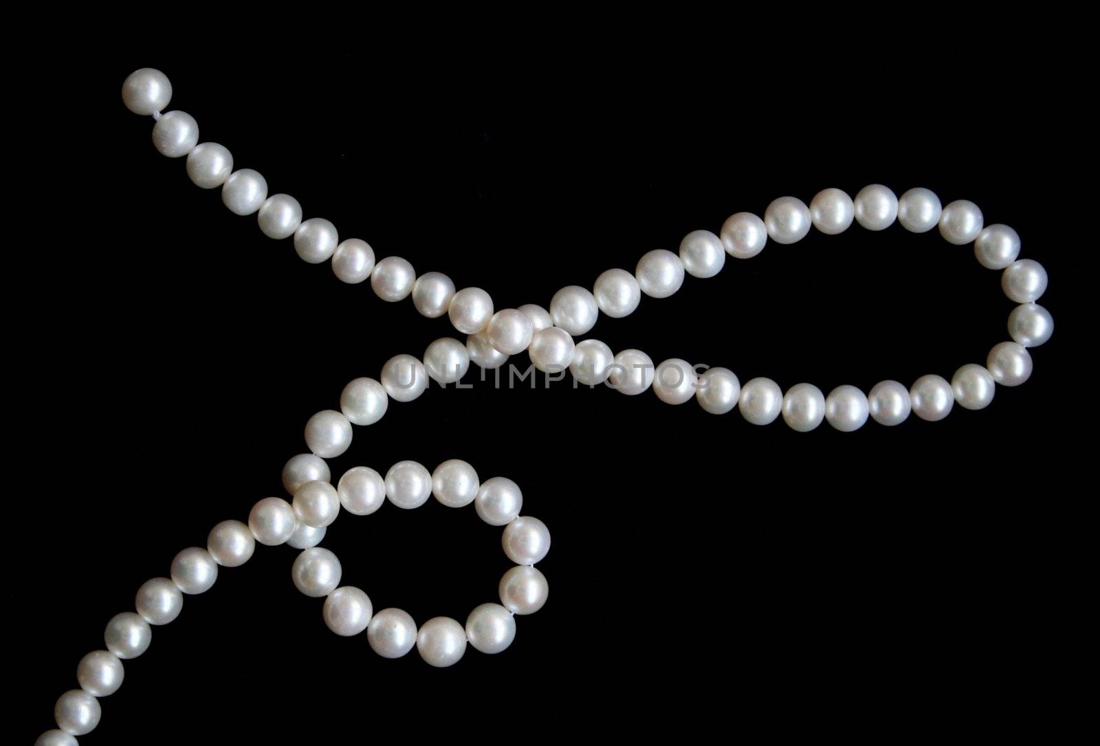 White pearls on the black velvet background 
