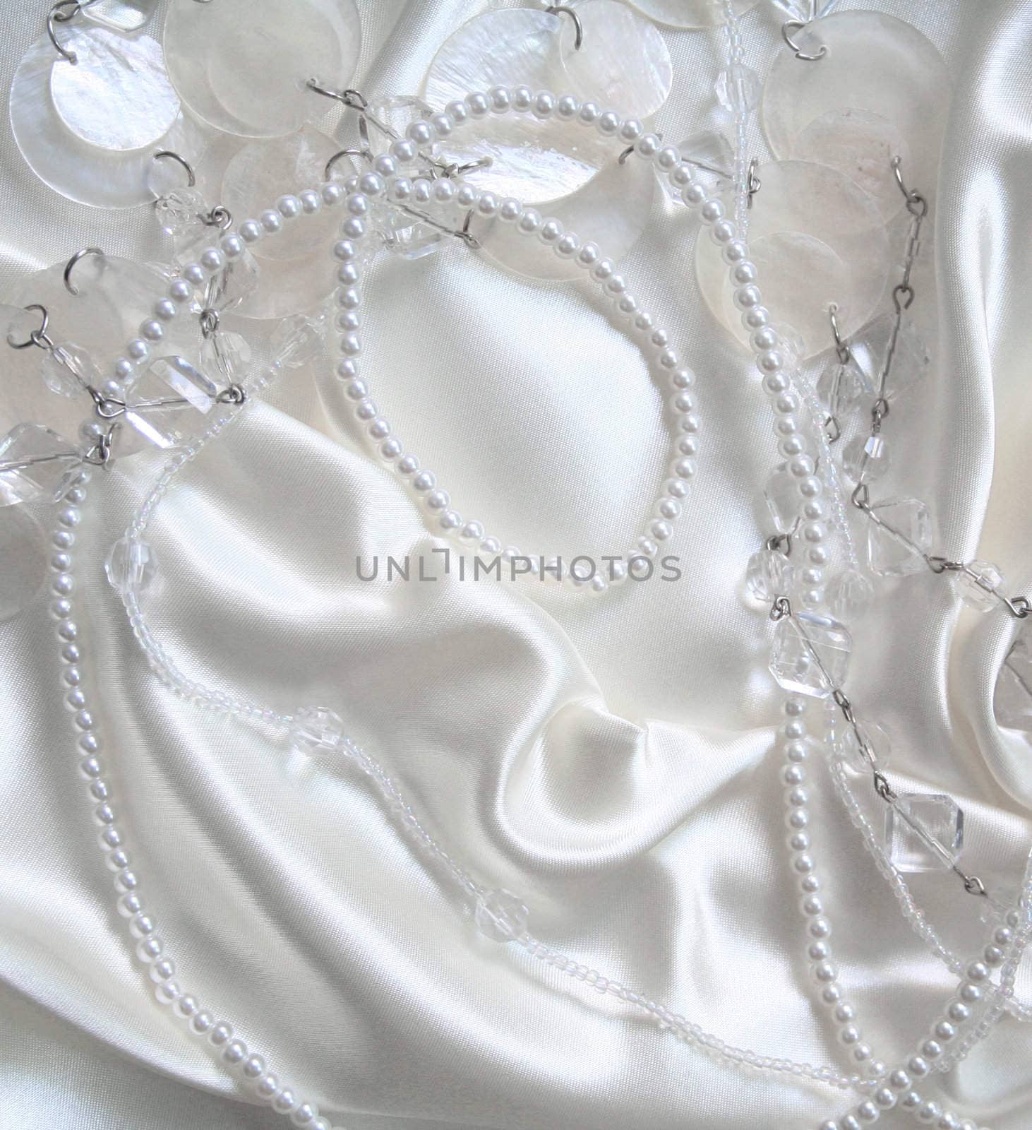 White pearls and nacreous beeds on white silk as wedding background 
