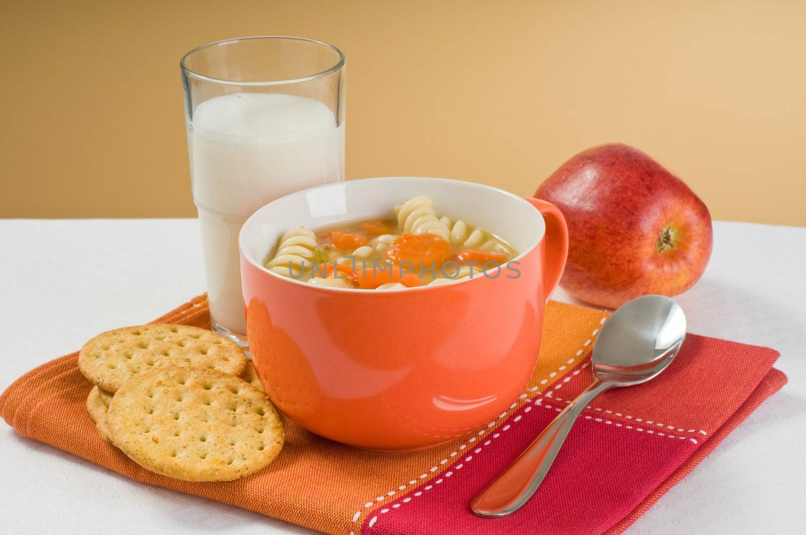 Healthy lunch of soup, crackers, apple and milk.