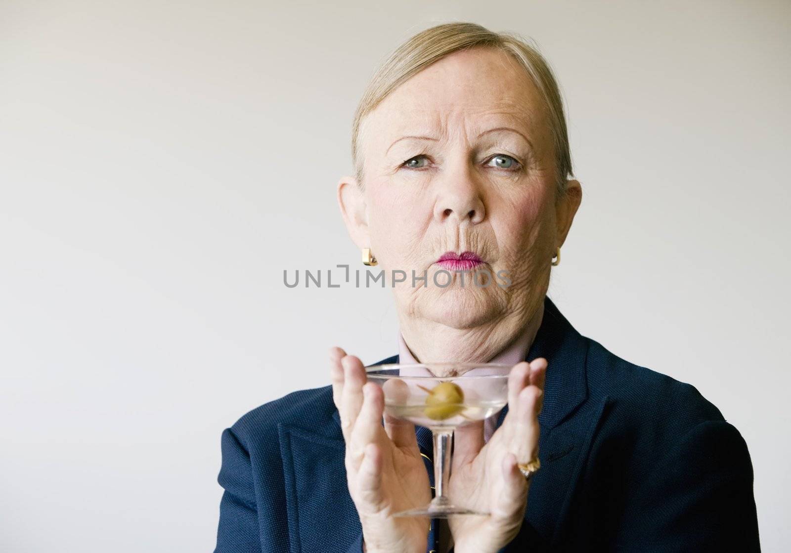 Dramatic senior woman in a man's suit holding a Martini.