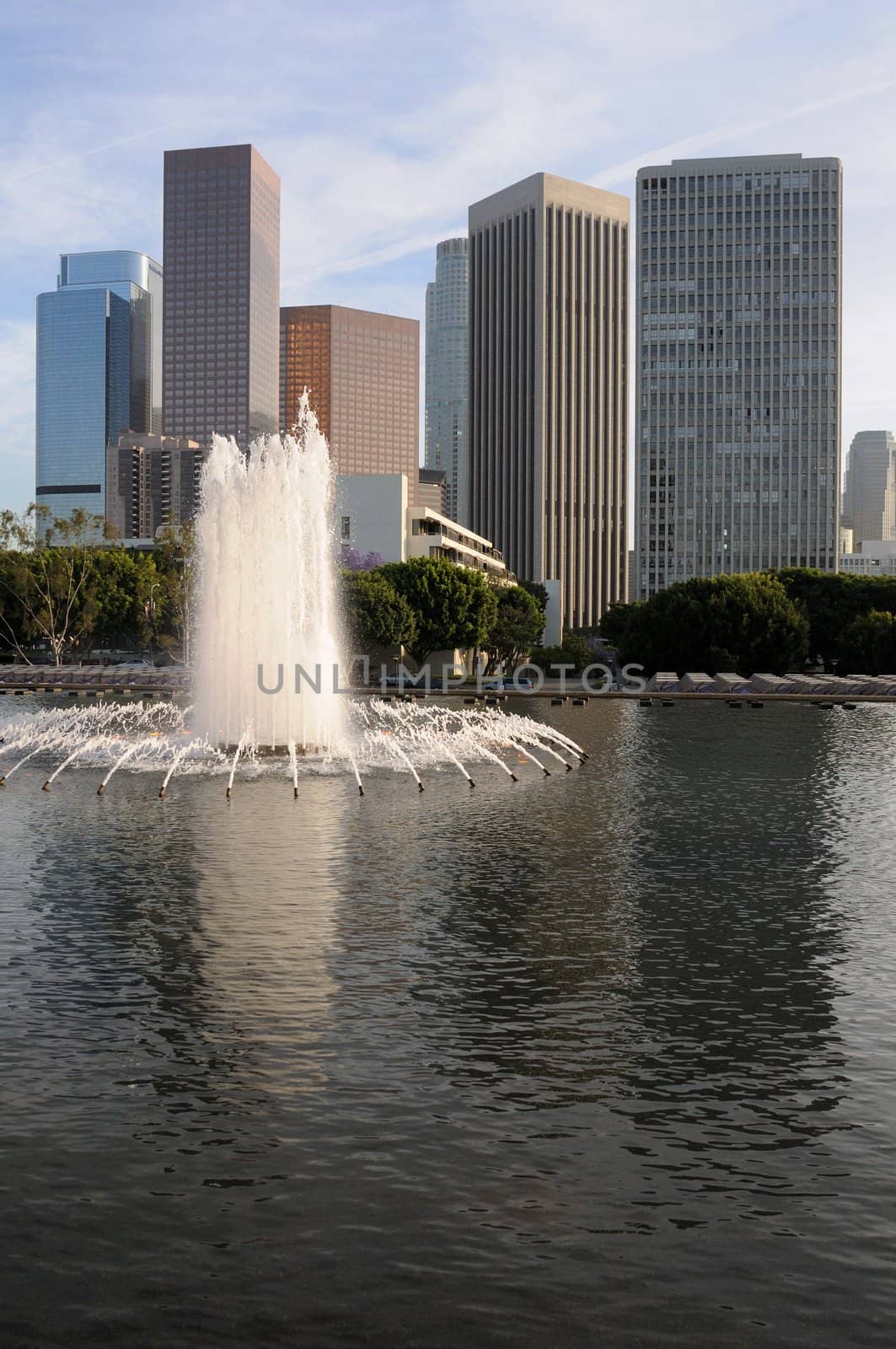 Downtown Los Angeles, California, with a cloudy blue sky and a water fountain and pool in the foreground.