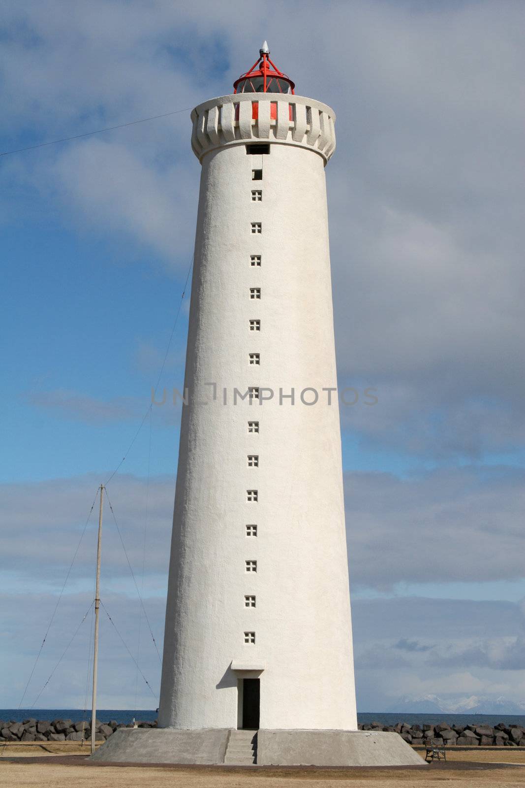 A big white lighthouse by the shore of the ocean