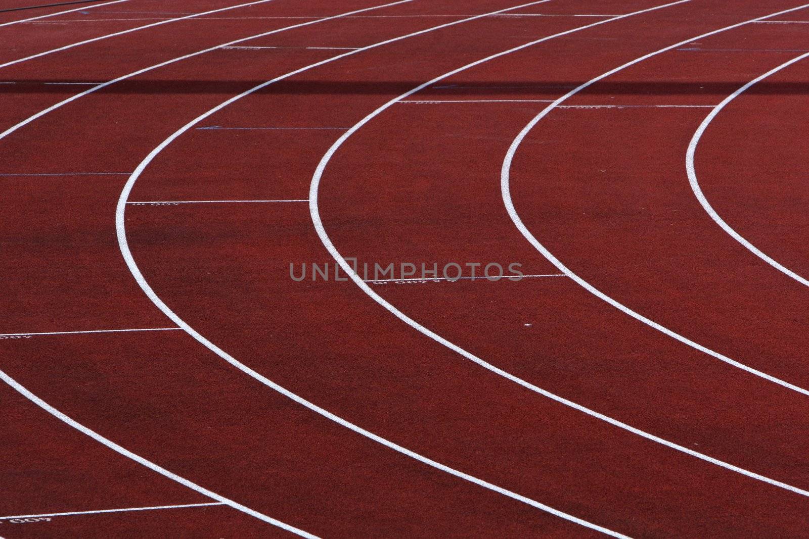 Curve on a red running track with white lines between the lanes