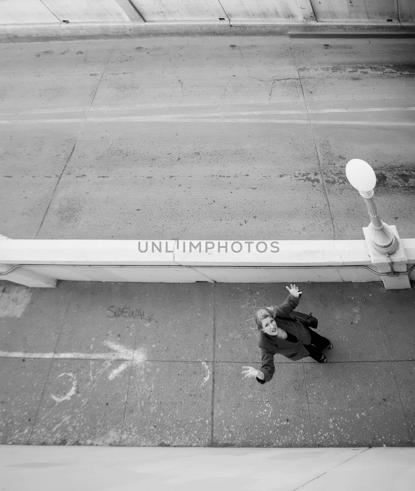 Wide shot from above of woman on a sidewalk with her hands in the air