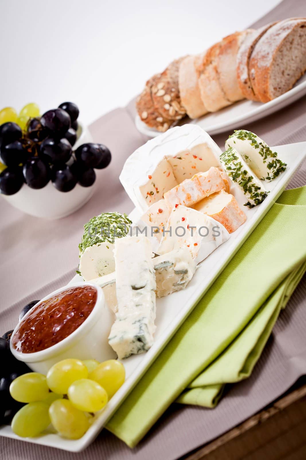 different cheese types on plate with grapes and red wine on wooden table
