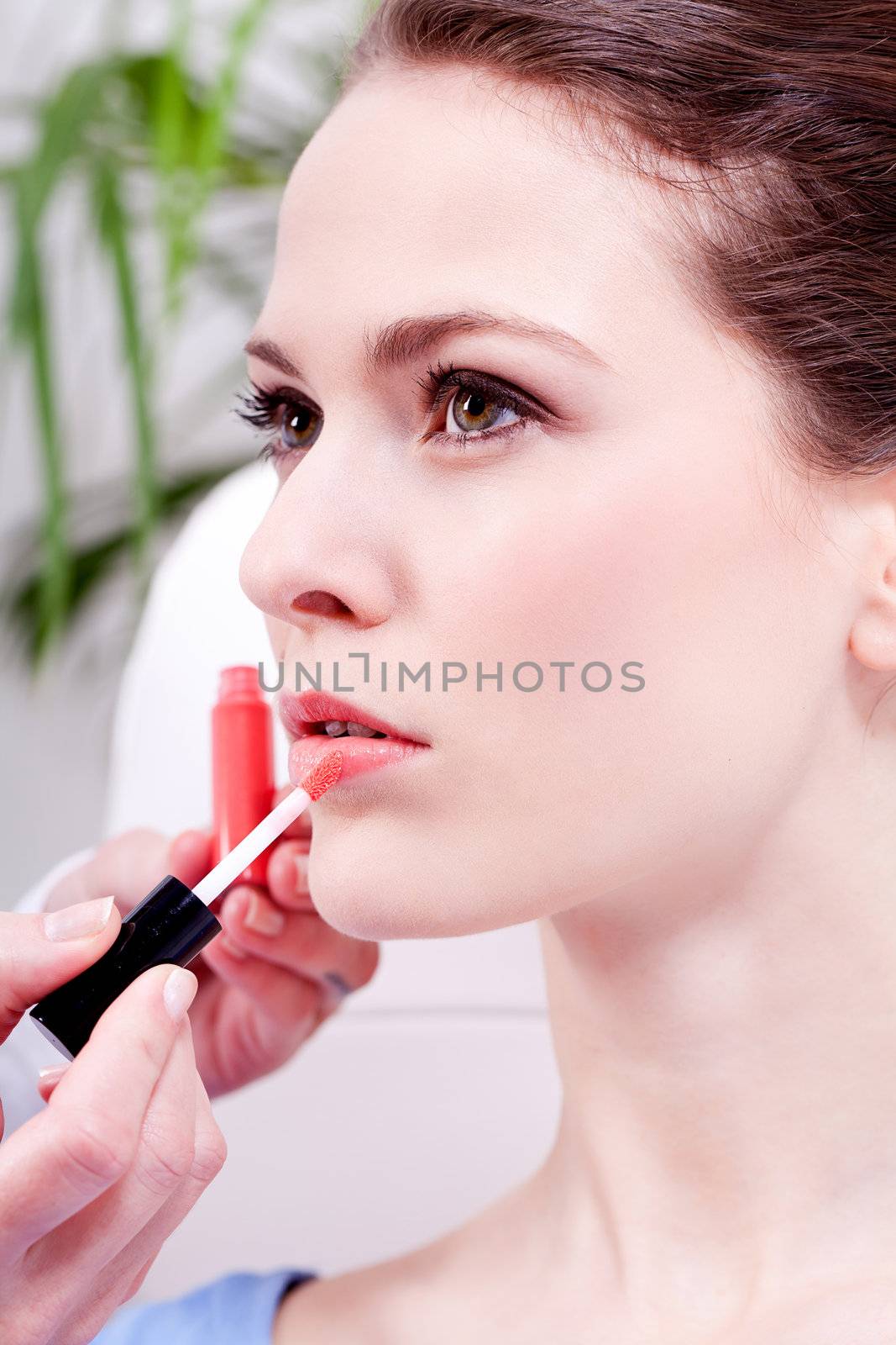brunette attractive woman portrait applying lipstick lipgloss in beauty salon