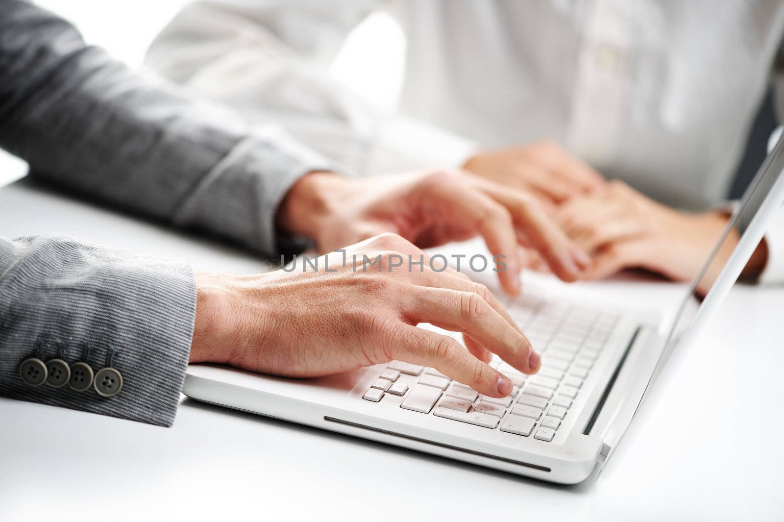 businessman typing on a white computer keyboard, woman on background