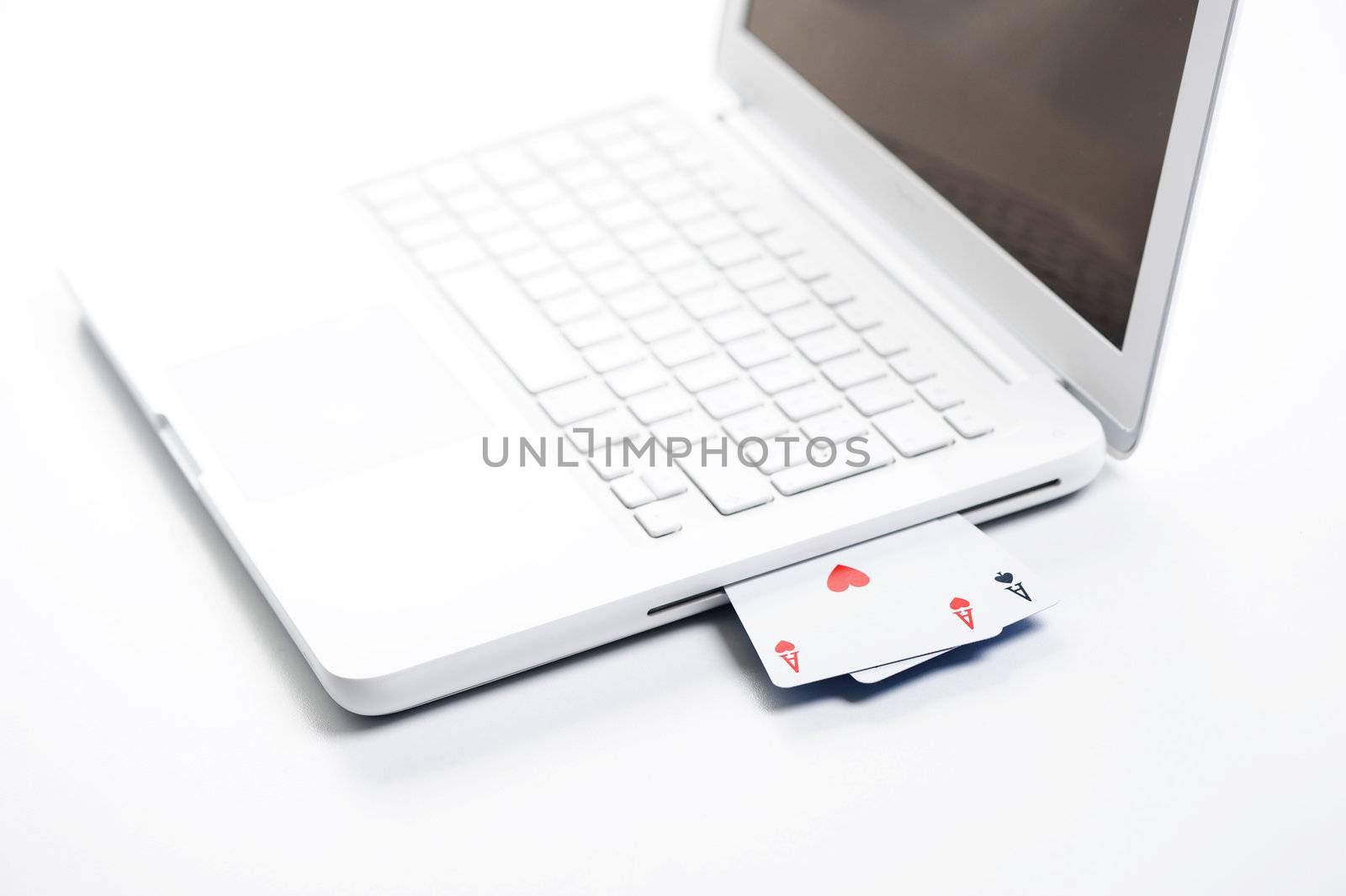 gambling online, aces on white laptop - concept photo by stokkete