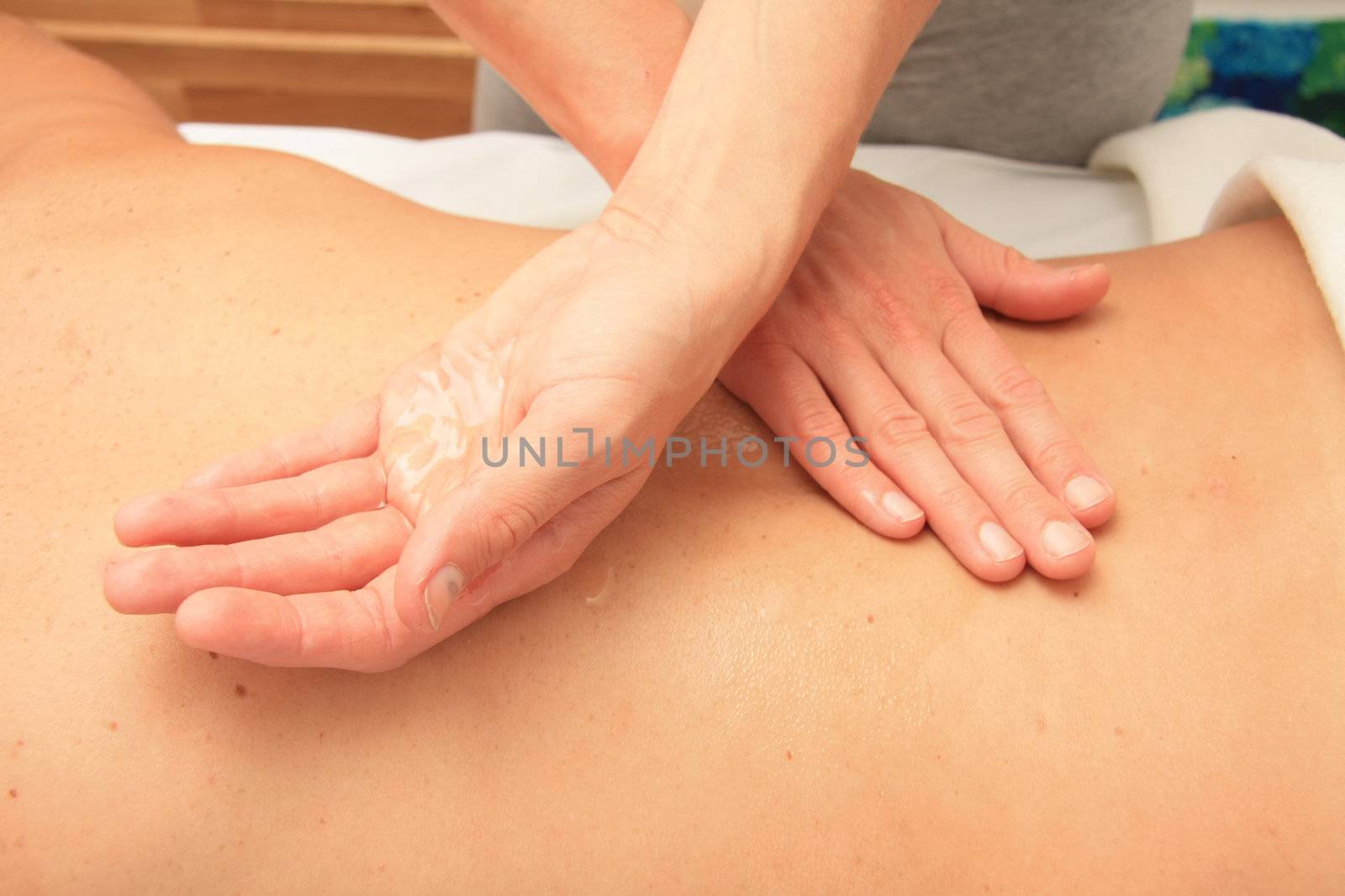 A female masseur preparing her hand with oil for a back massage