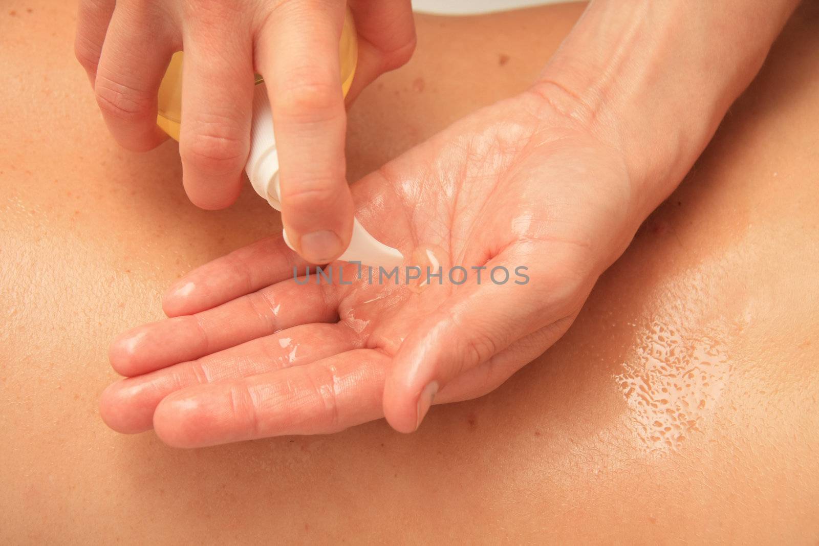 A female masseur preparing her hand with oil for a back massage