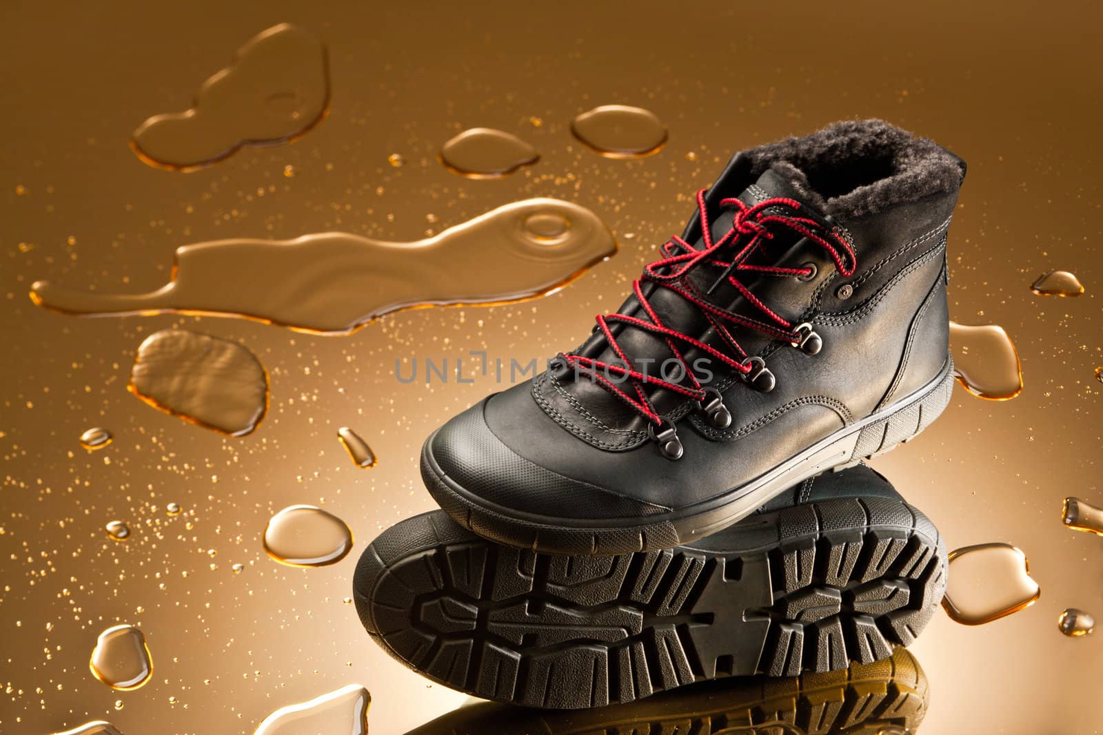 black winter shoes over golden background with water drops