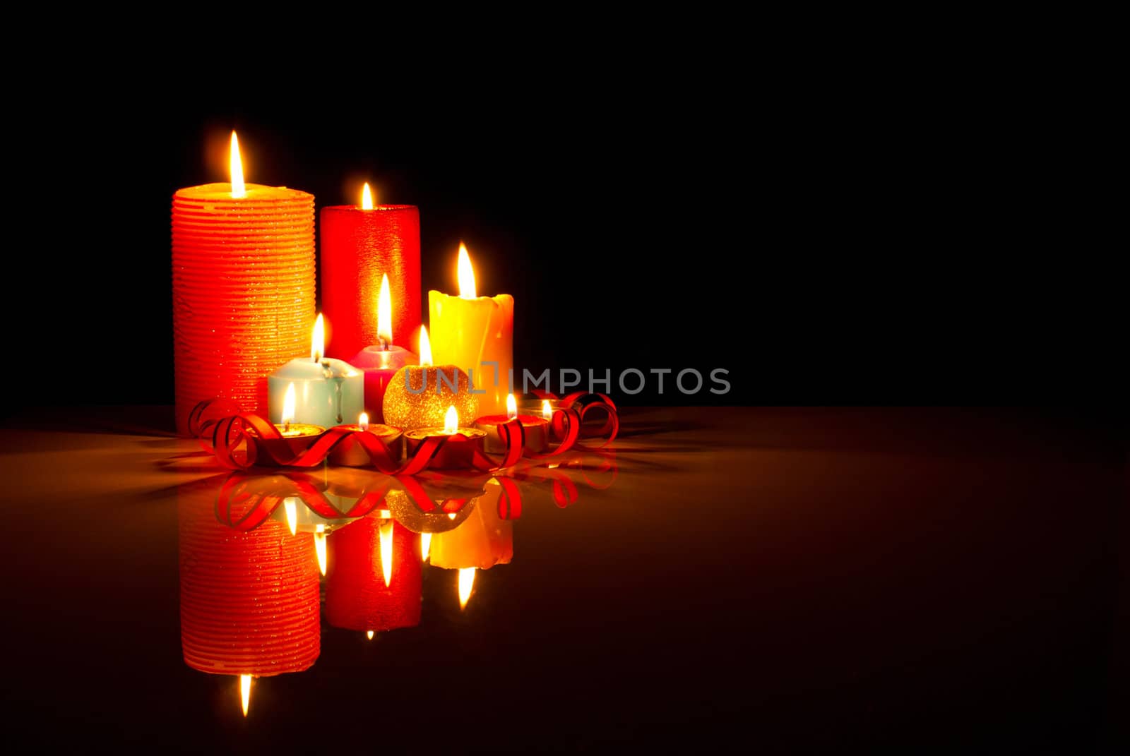 A lot of burning colorful candles against black background