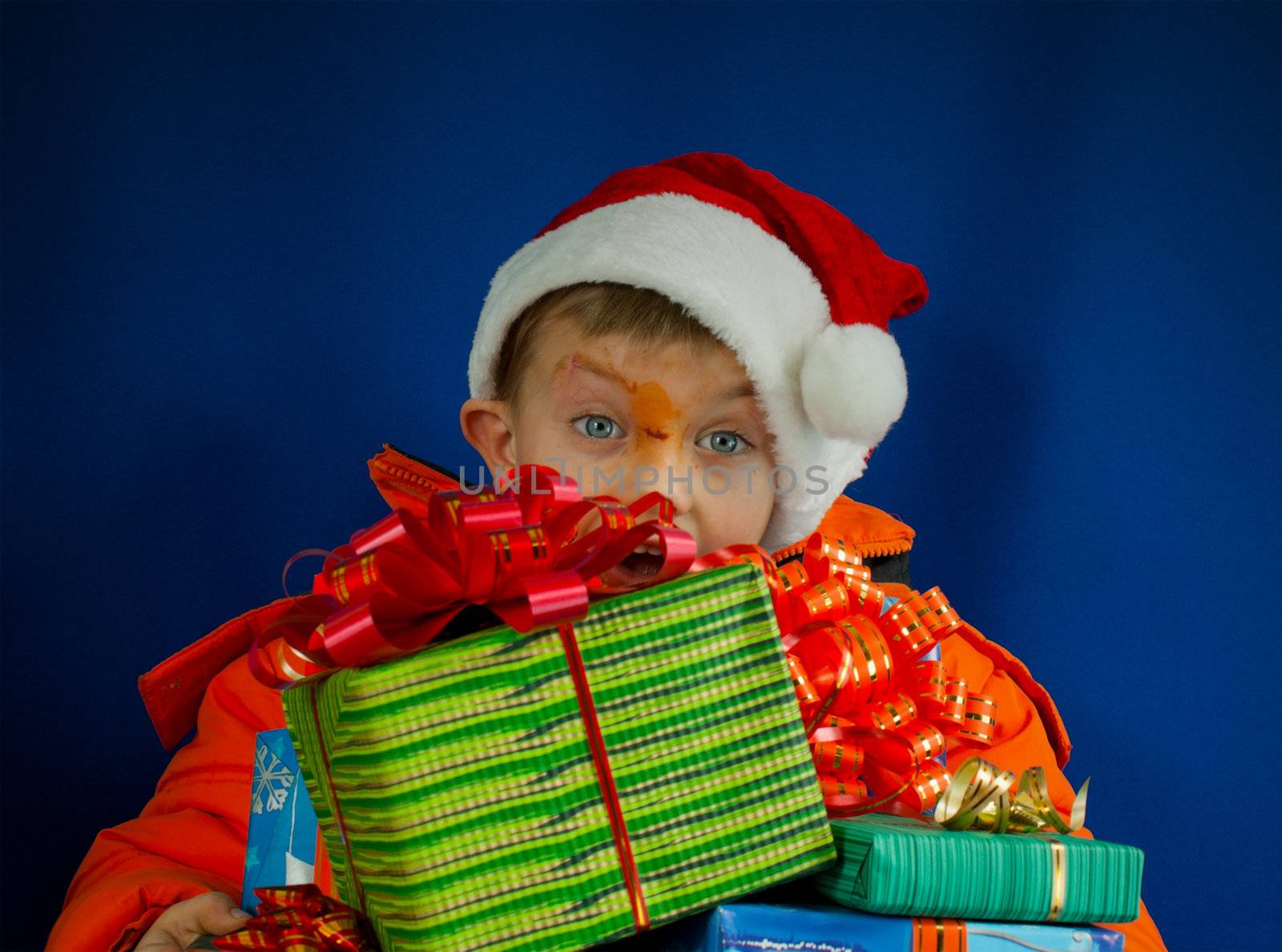 Surprised boy looking from behind the Christmas presents by AndreyKr