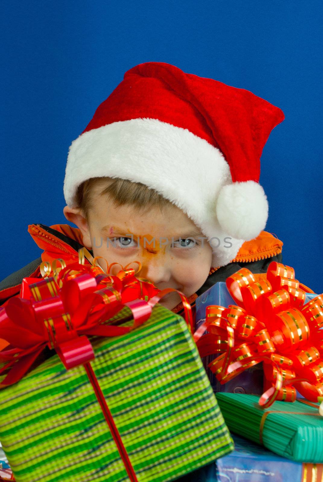 Surprised boy looking from behind the Christmas presents