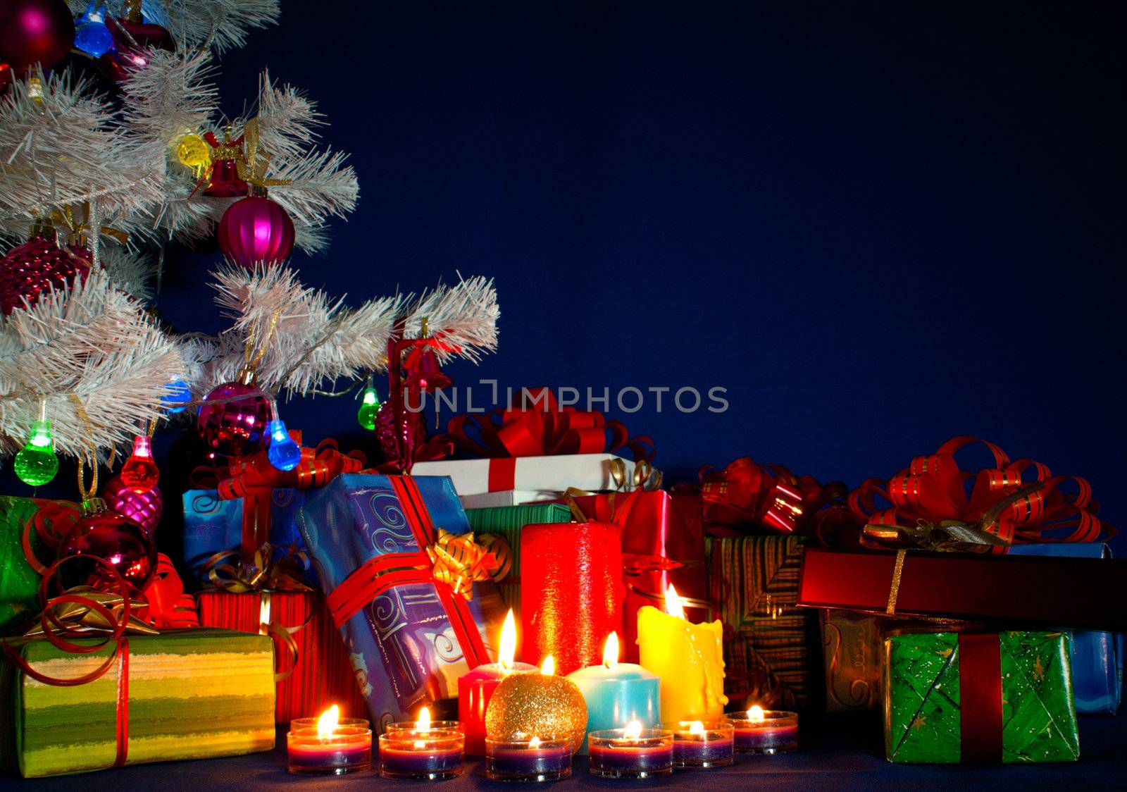 Christmas presents and burning candles against blue background