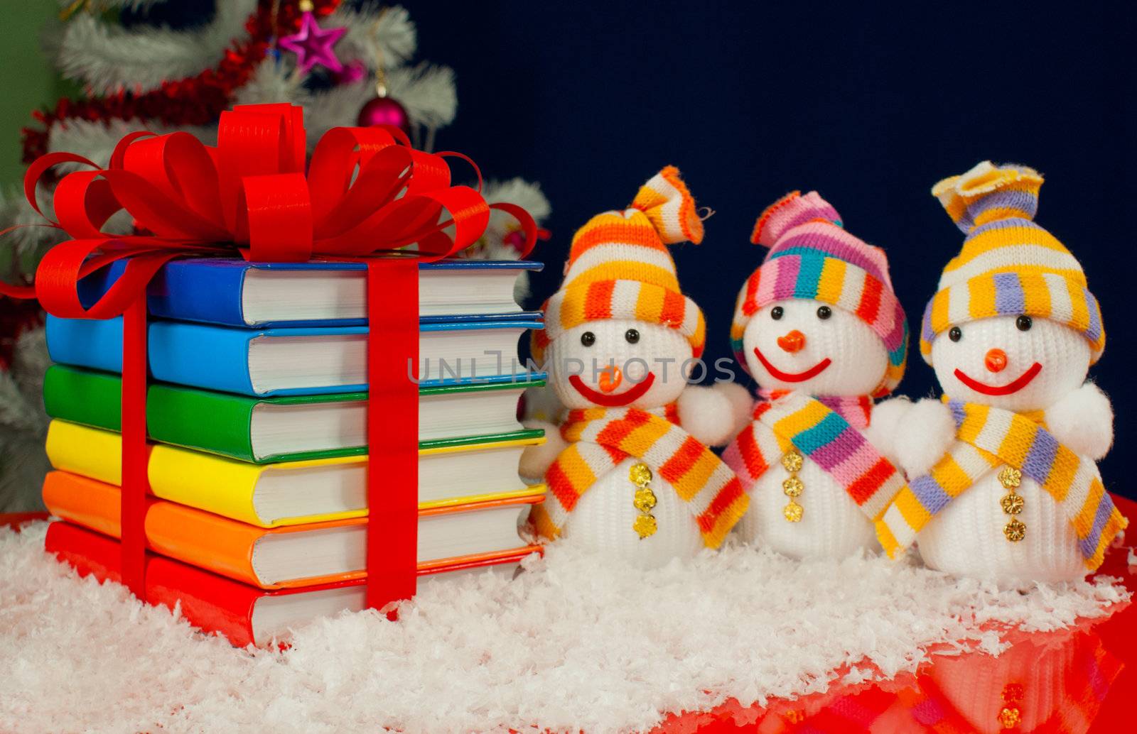 Stack of colorful books tied up with red ribbon and three snowmen