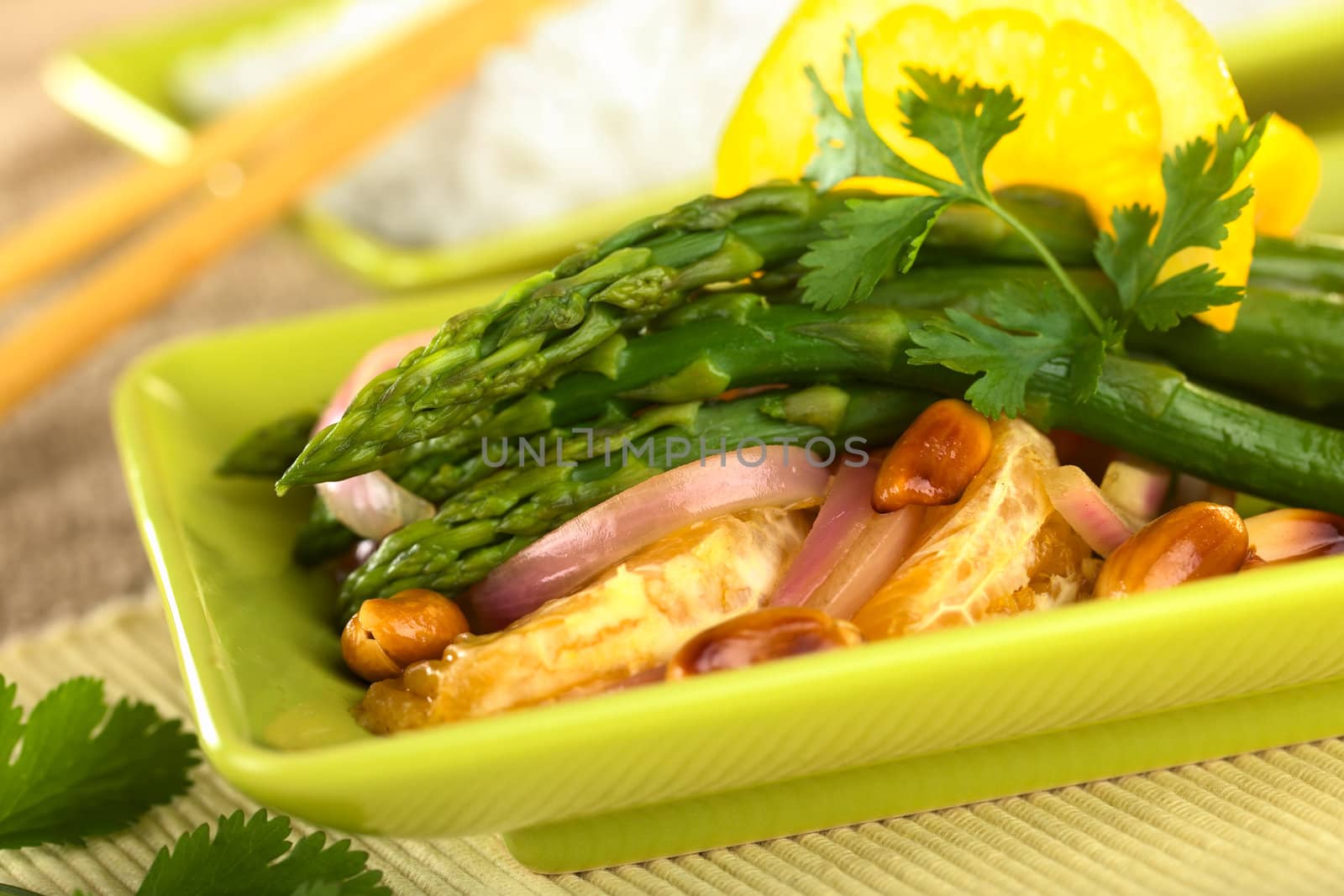 Green asparagus prepared in Thai-style with oranges, onions, cilantro and peanut in an orange-ginger sauce (Selective Focus, Focus on the asparagus head on the top)