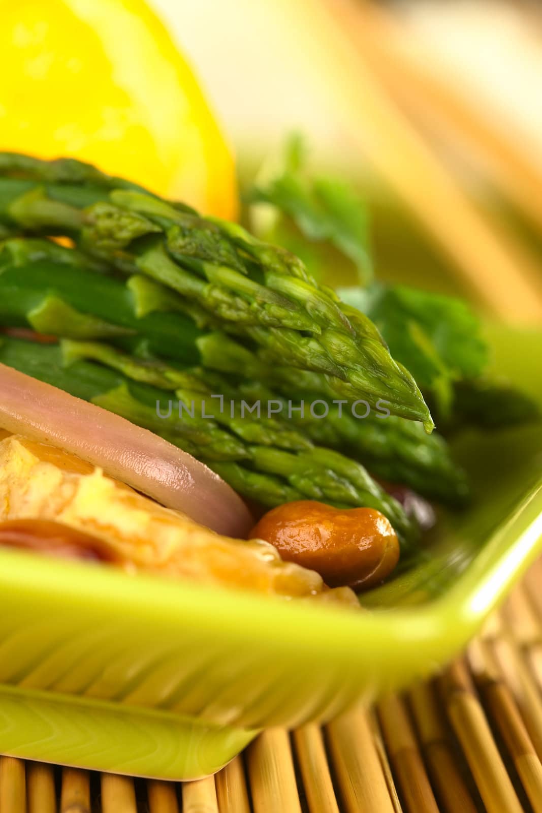 Green asparagus prepared in Thai-style with oranges, onions and peanut in an orange-ginger sauce (Selective Focus, Focus on the asparagus head on top)