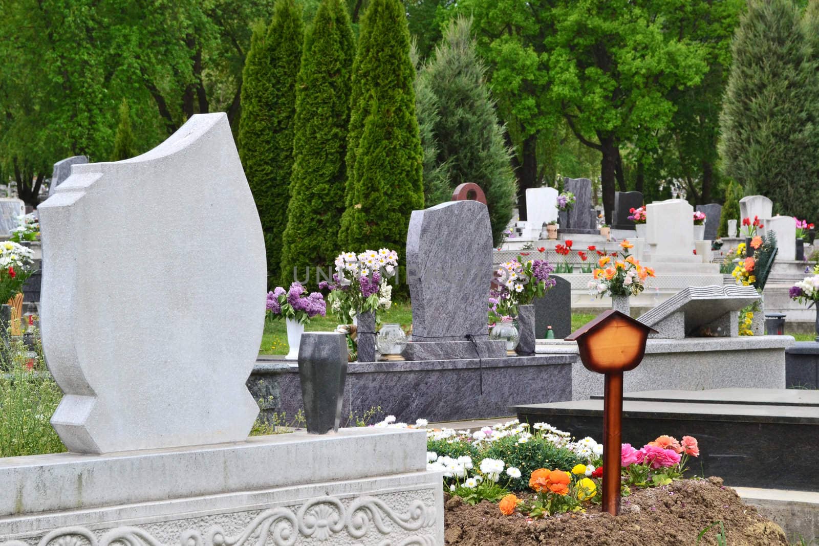 Tidied, well-kept cemetery with tombstones, ornamental plants and colourful flowers.