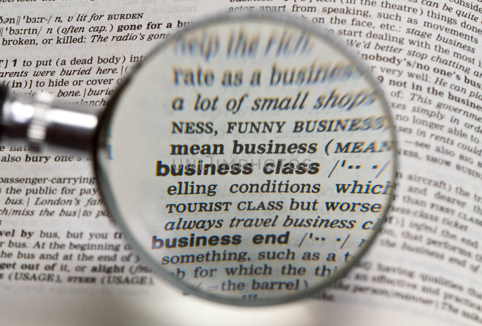 the word business class in dictionary magnified by handheld magnifying glass