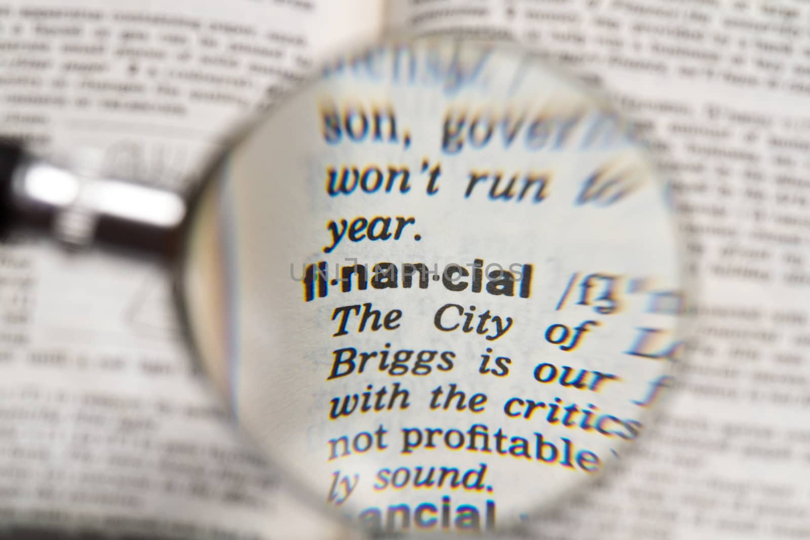 the word financial in dictionary magnified by handheld magnifying glass
