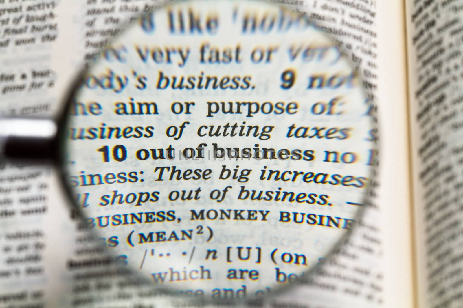 the phrase out of business in dictionary magnified by handheld magnifying glass