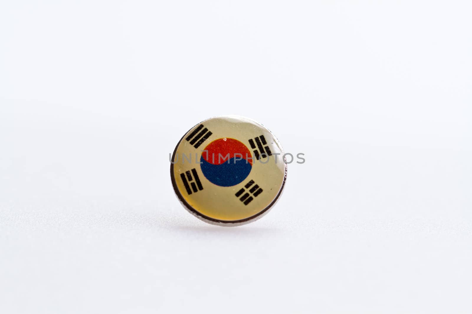 the South Korea flag sysmbol on thumbtack on white surface