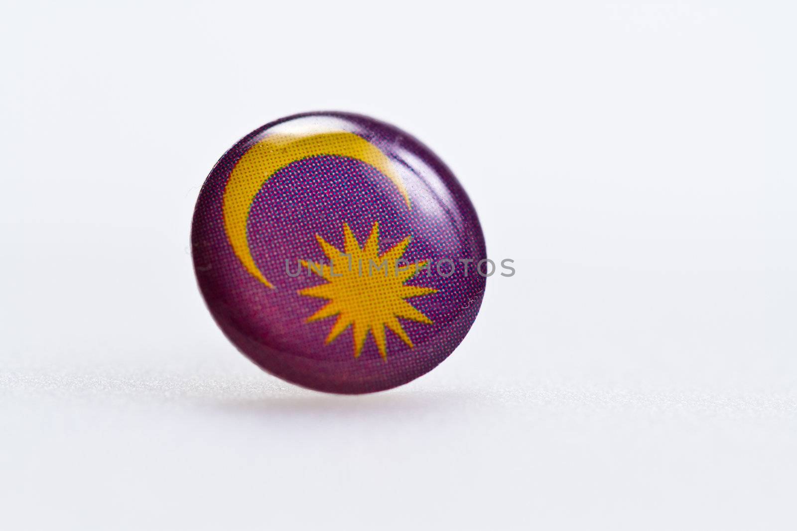 Malaysian flag symbl on thumbtack on white surface