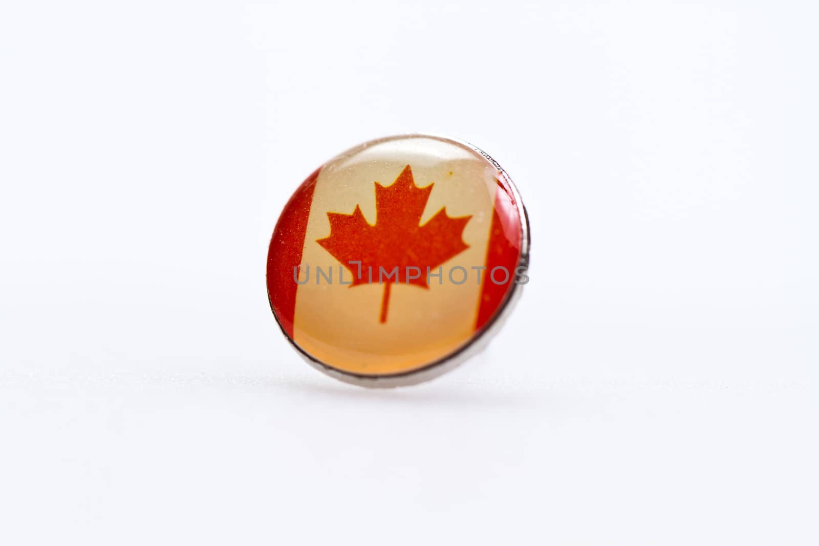Canada flag symbl on thumbtack on white surface