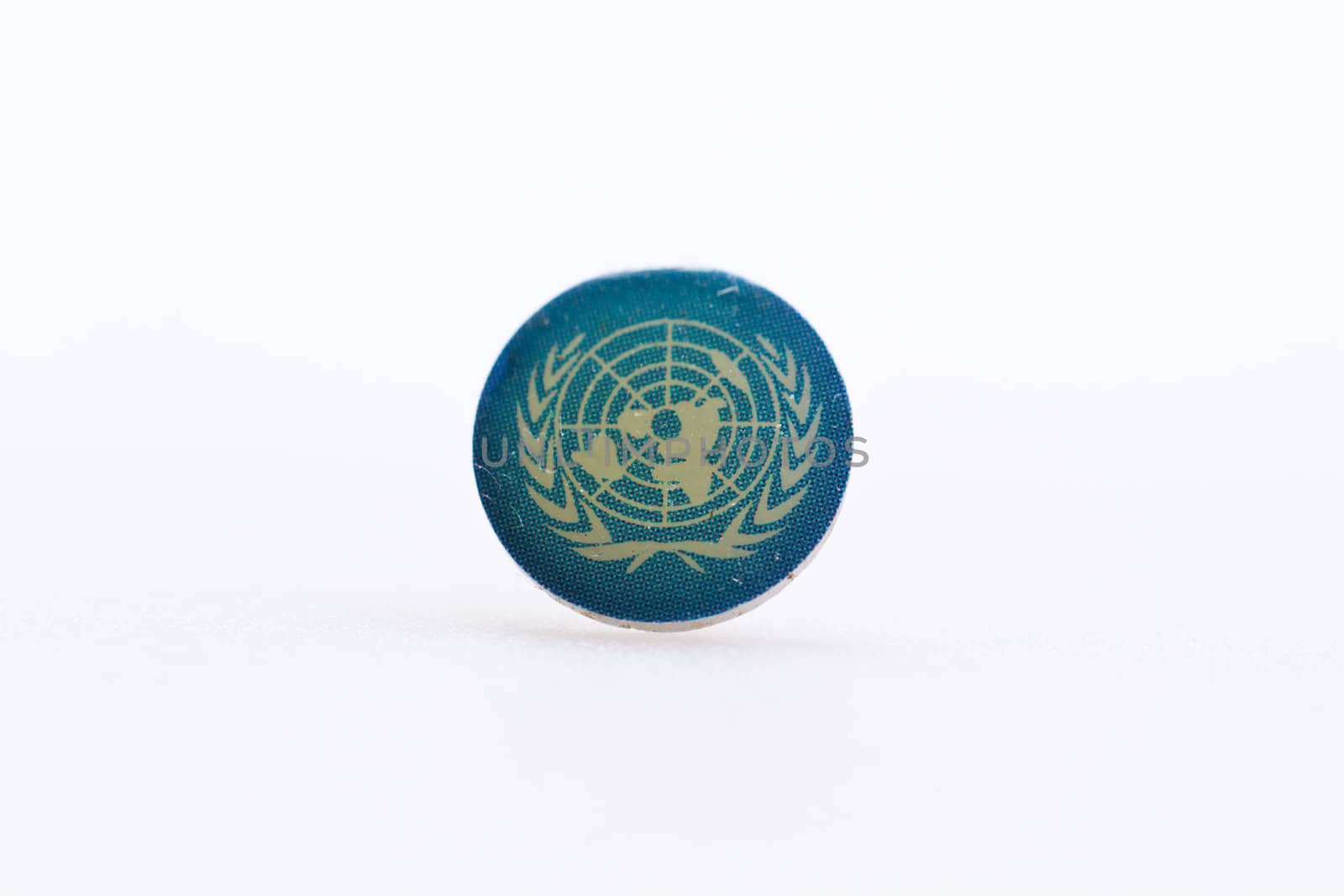 United Nation flag symbol on metal thumbtack on white surface