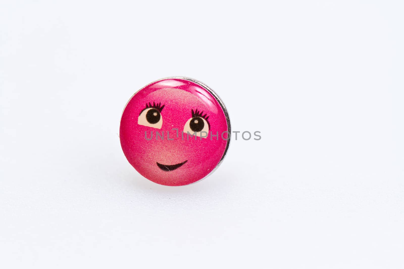 smiley character on metal thumbtack on white surface
