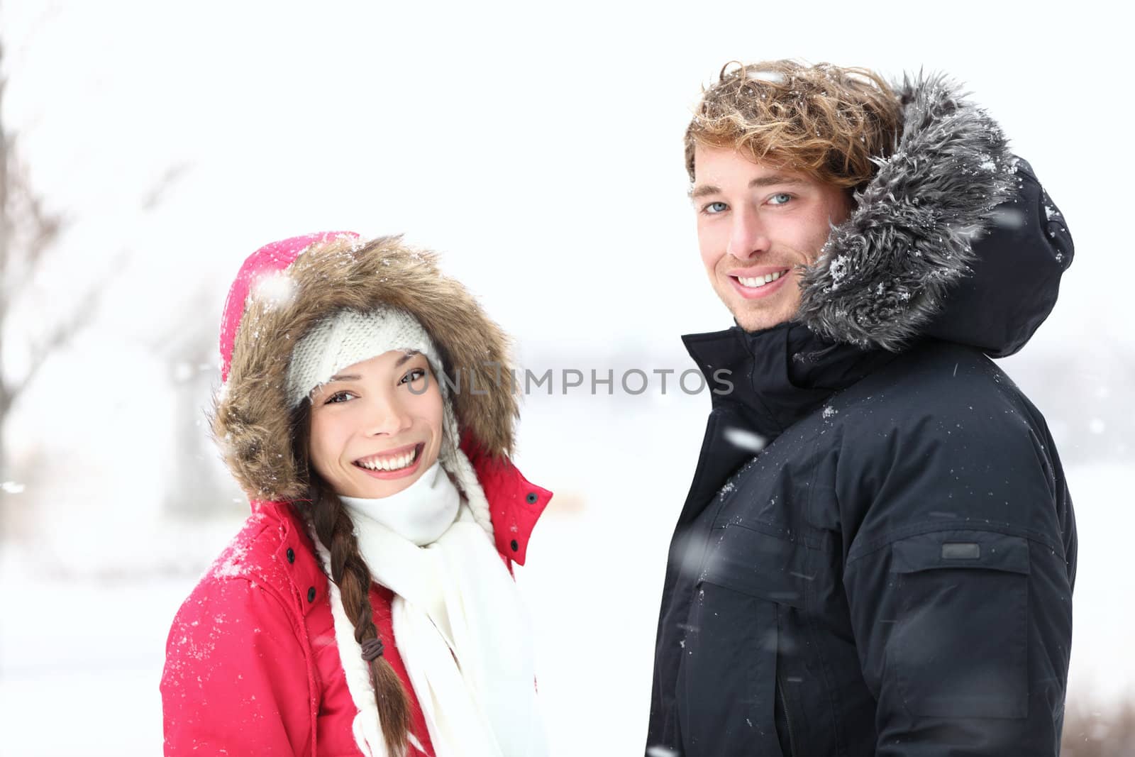 Winter people. Young couple in snow outdoor on winter day. Caucasian man, Asian woman in their twenties.