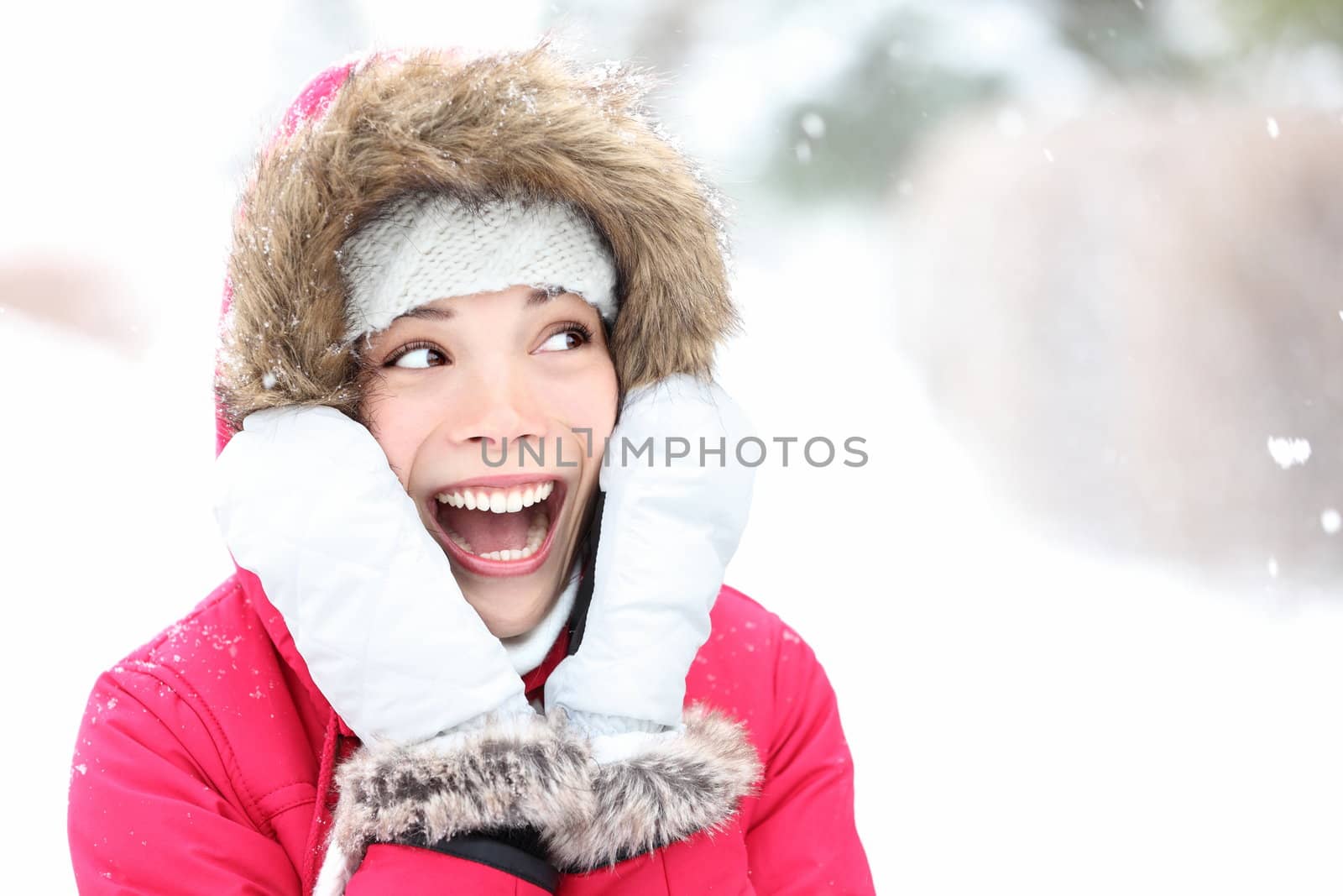 Excited winter woman looking to side smiling happy and joyful holding head. Beautiful mixed race asian cauasian girl playful in the snow.