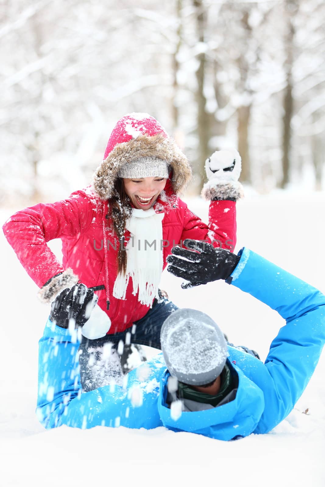 Winter couple snowball fight. Young couple having fun in snow outside. young couple in their twenties.