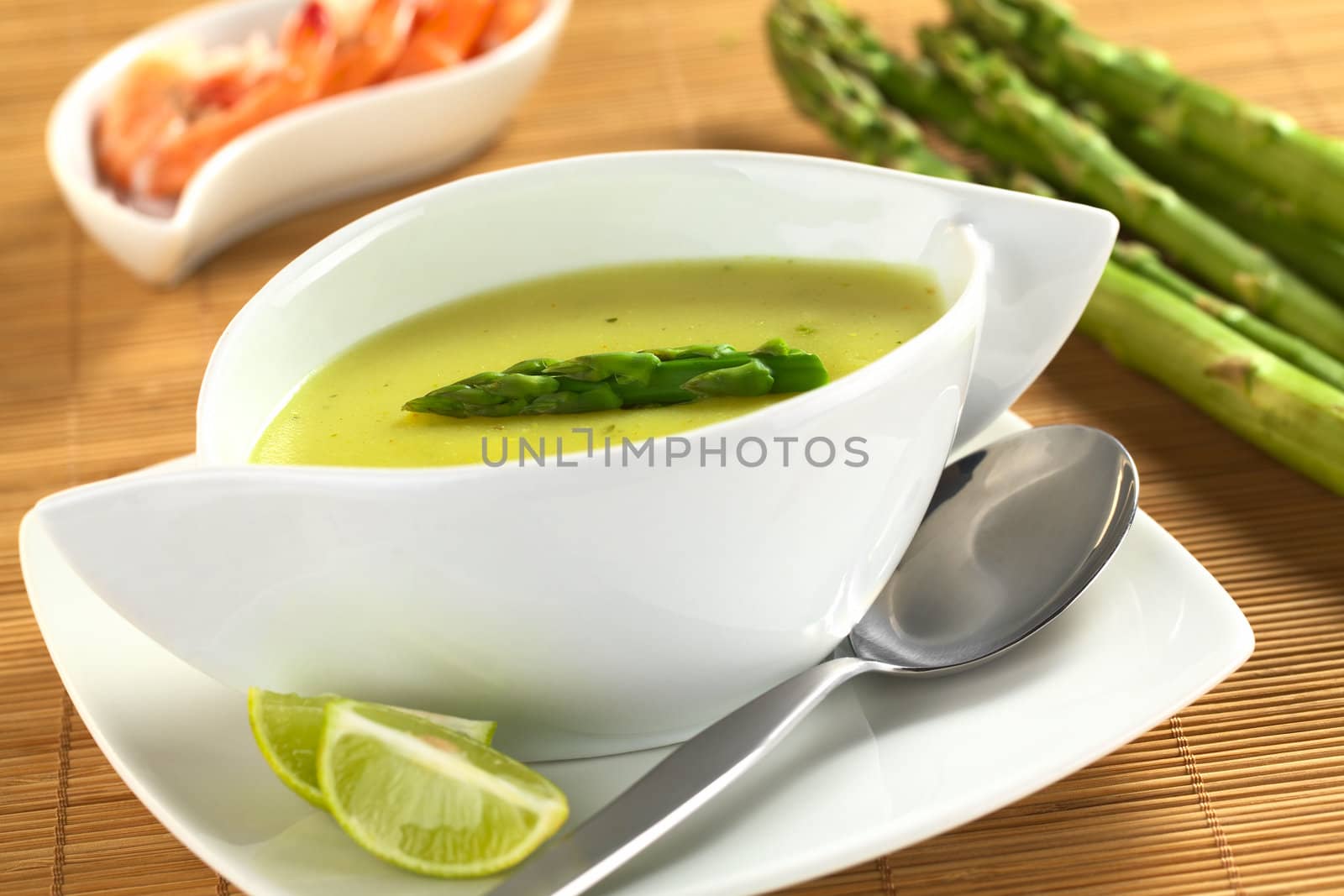 Cream of green asparagus with shrimps in the back (Selective Focus, Focus on the asparagus head on the soup)