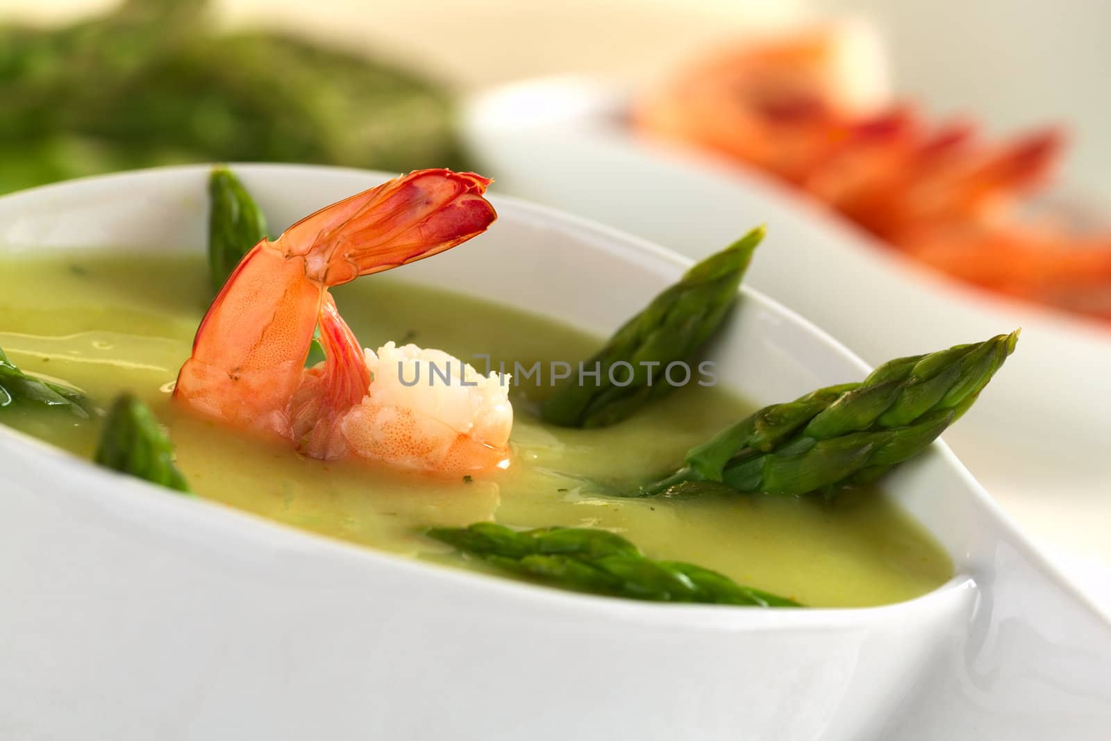 Cream of green asparagus with shrimp (Selective Focus, Focus on the front of the shrimp)