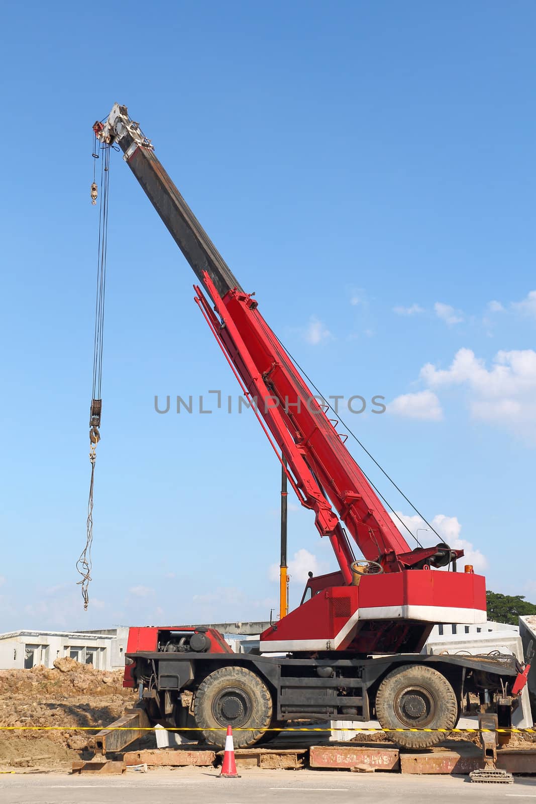 Red automobile crane against blue sky 