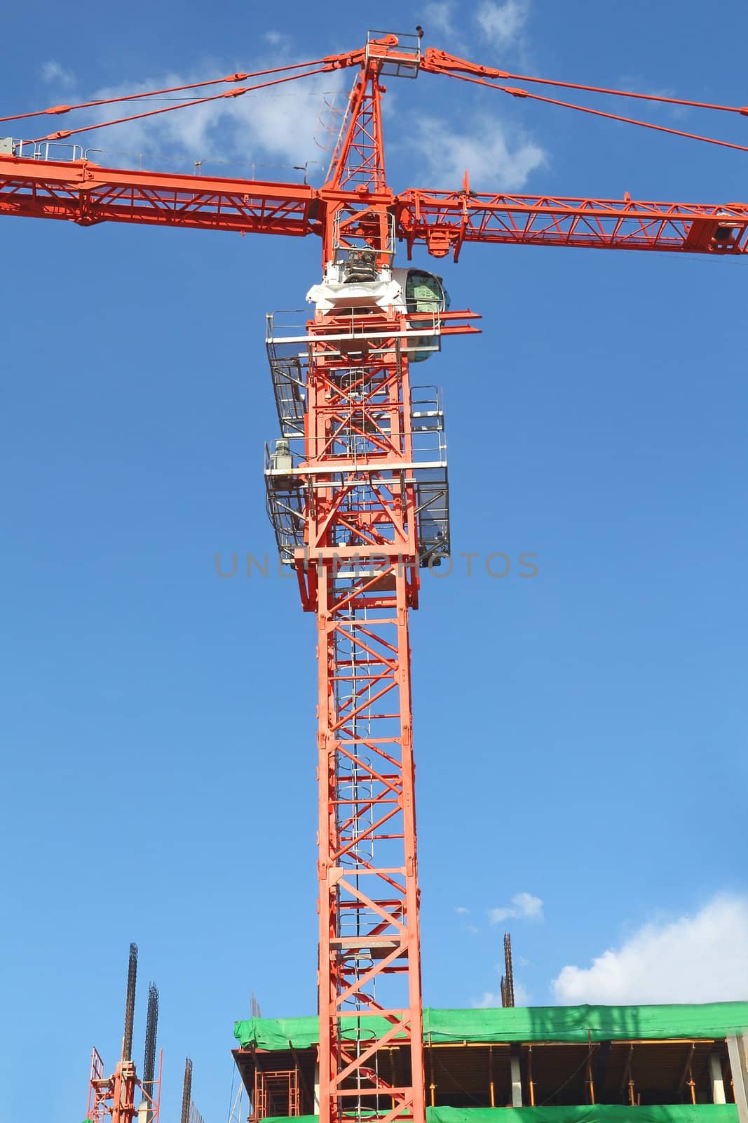 Red building crane against blue sky at construction site