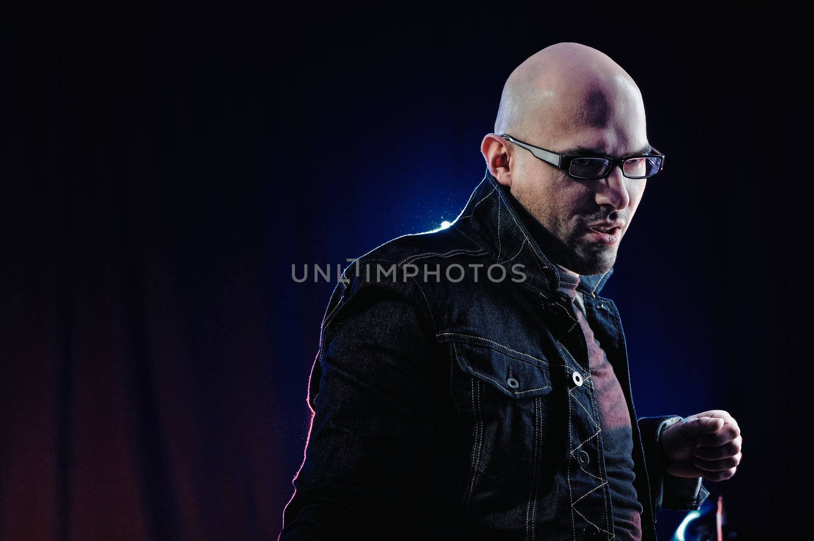 Man with glasses and in denim jacket. Studio-style portrait