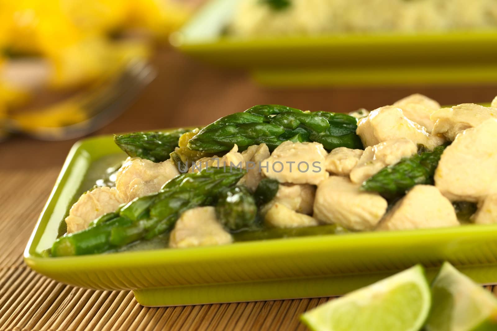 Green asparagus and chicken fricassee with rice in the back (Selective Focus, Focus on the asparagus tip in the middle of the image)