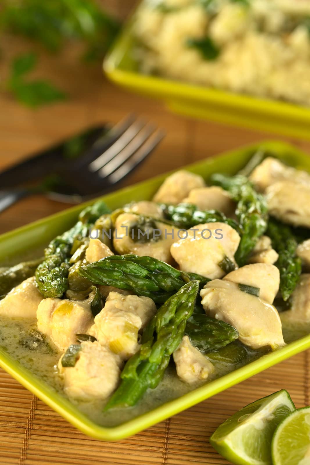 Green asparagus and chicken fricassee with rice in the back (Selective Focus, Focus on the asparagus tip in the middle of the image)