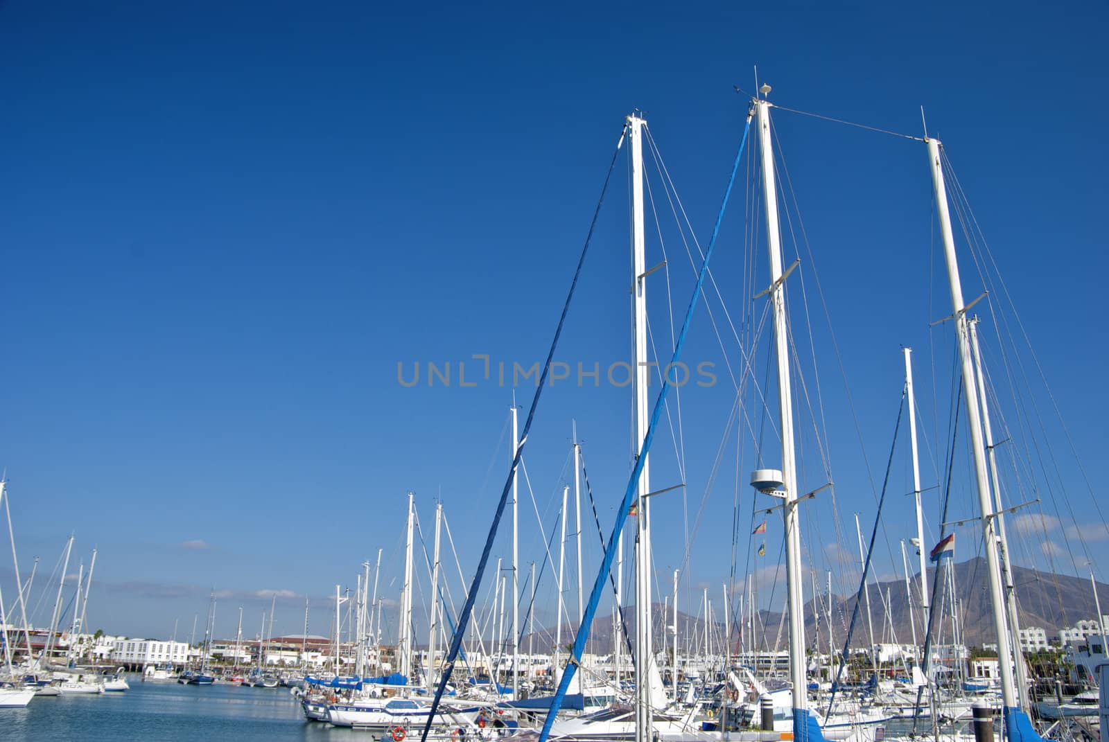 A Yacht Marina in Lanzarote Canary Islands with a forest of Masts and Mountains in the Background