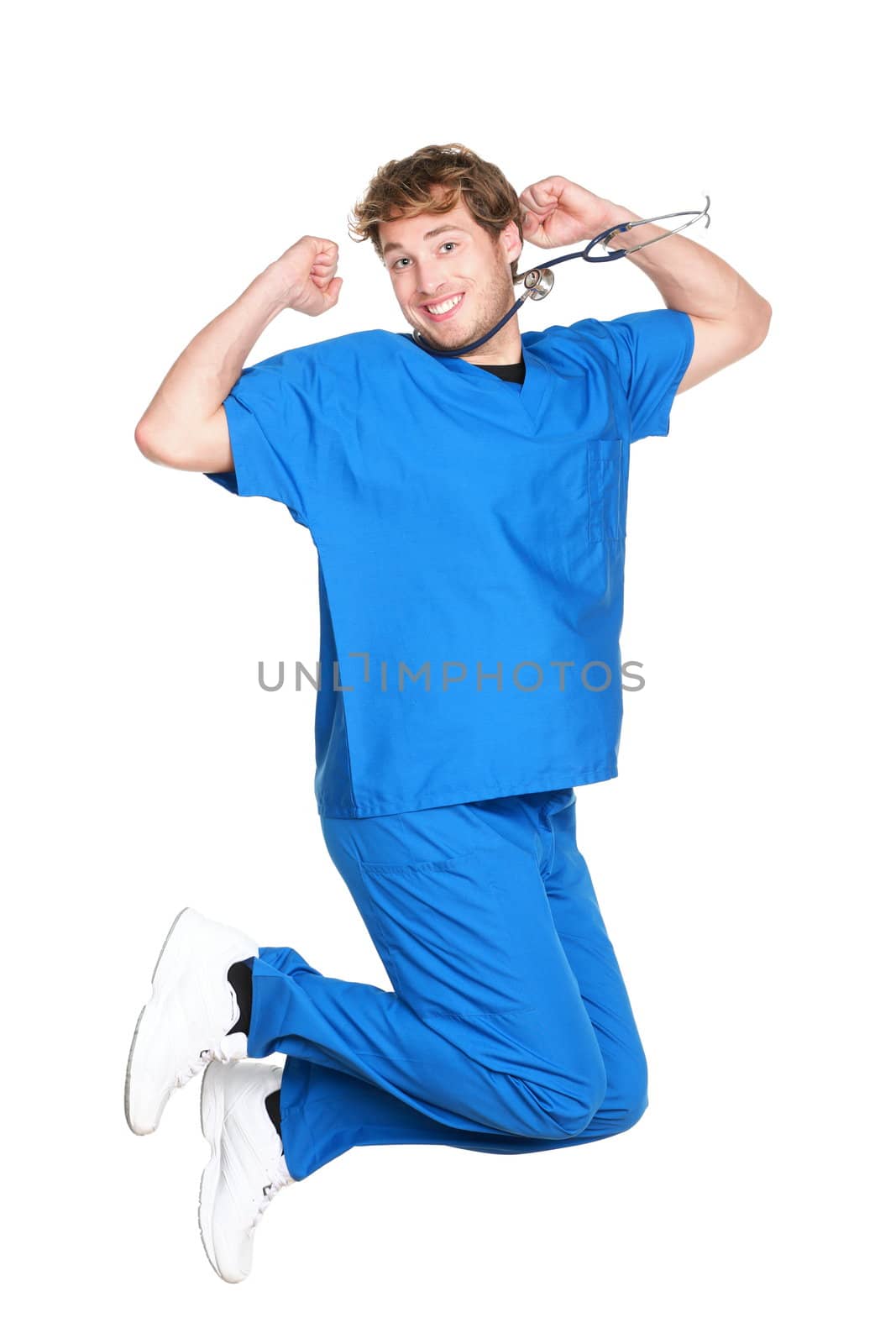 happy male nurse or doctor jumping in blue scrubs smiling excited. Young medical professional. Caucasian man in his twenties wearing stethoscope isolated on white background.