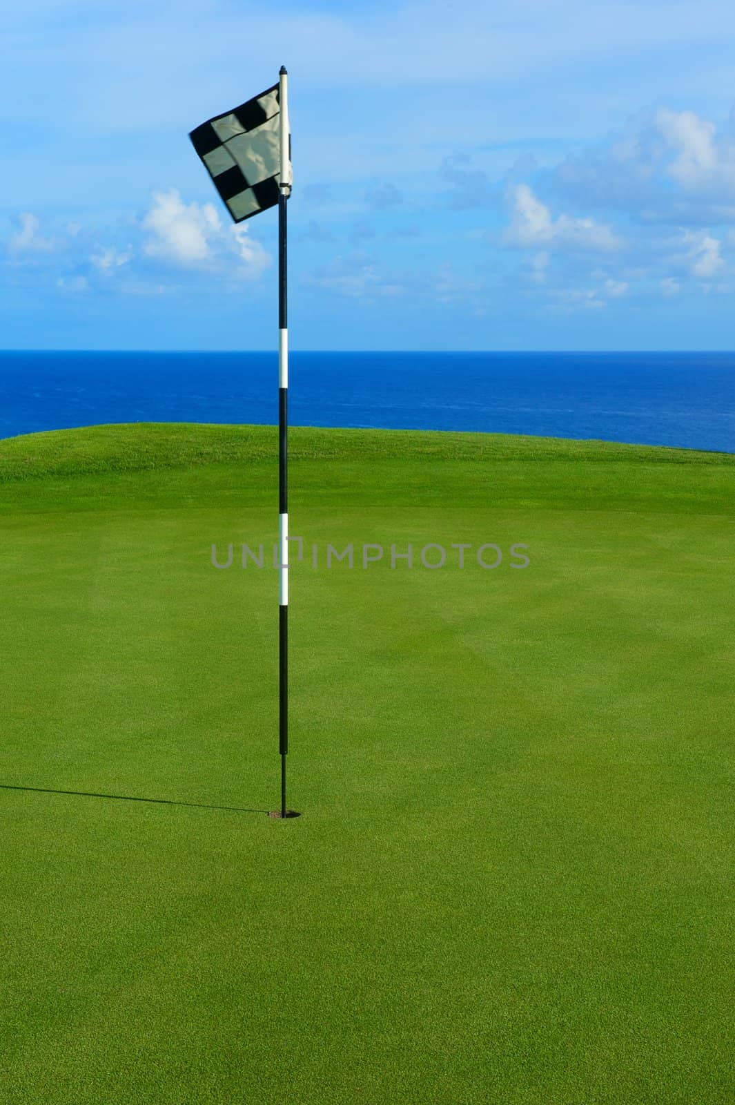 This is a flag and pin on the tee of a golf course in Hawaii overlooking the Pacific Ocean