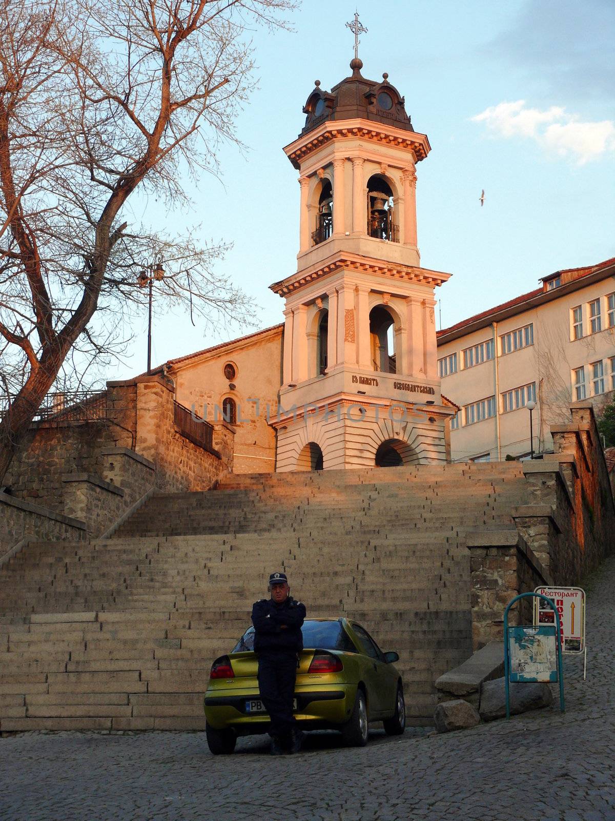 Plovdiv, Bulgaria - April 03, 2010: Policeman staying near the car in front of Saint Godmother Church. Plovdiv, Bulgaria