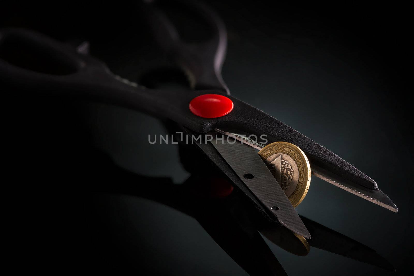 Turkish lira currency coin metaphor with scissors trying to cut isolated on black background