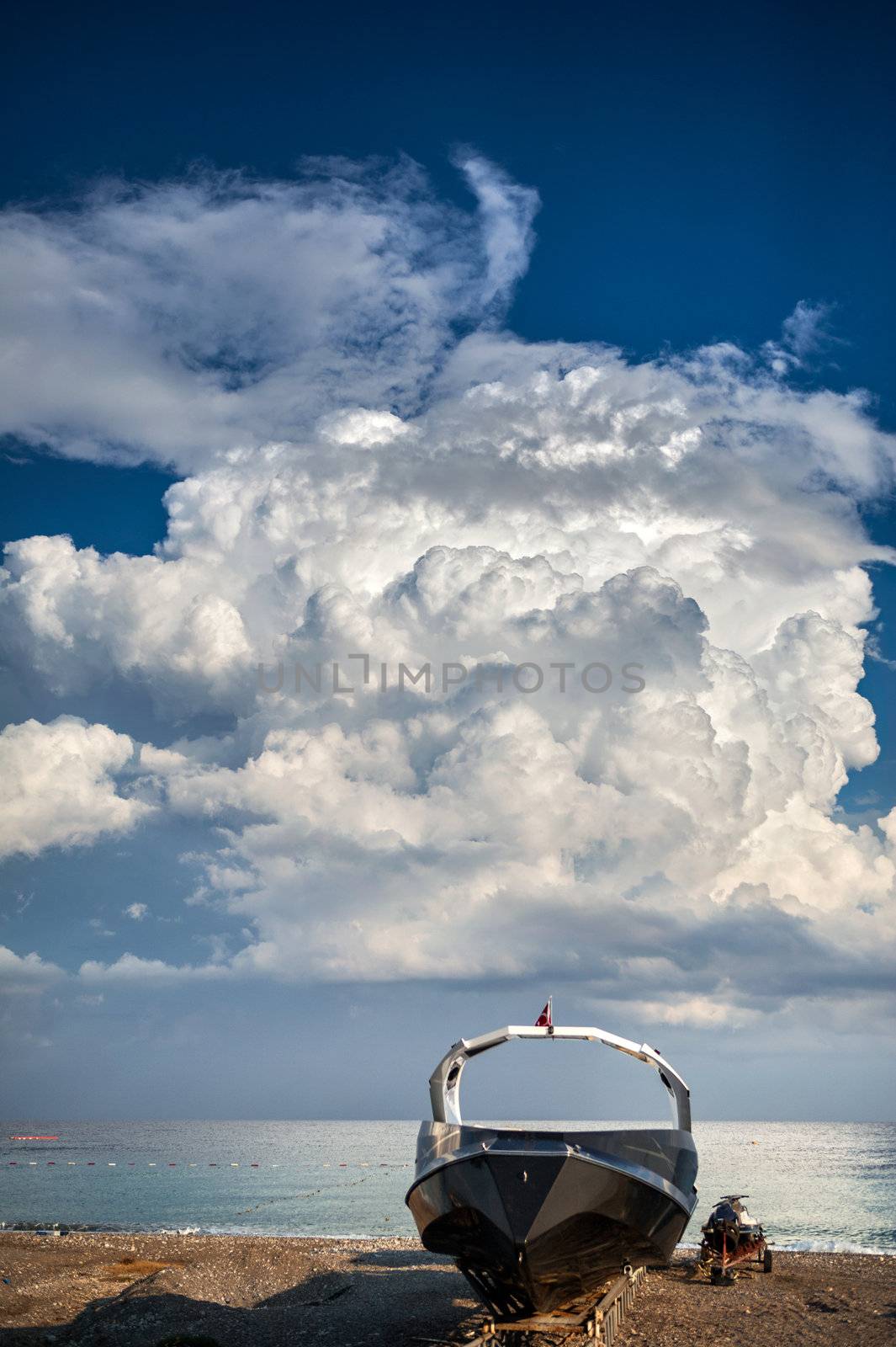 Sports boat and scooter on the beach over dramatic sky with cumulus clouds